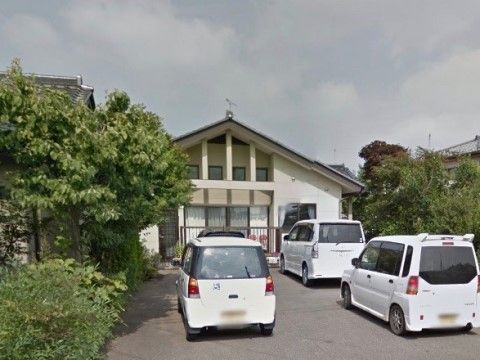 建物の前に複数台の車が縦列駐車をしている。緑に溶け込むデザインの施設で、自宅のような雰囲気がただよう。