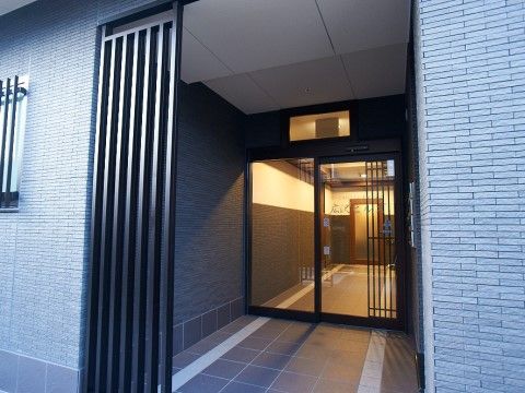 ガラス窓になった玄関扉の奥に見える、オレンジ色の光が灯るエントランス