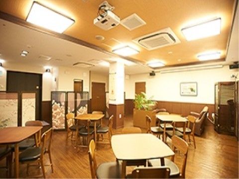 室内にはテーブルと椅子が置かれ、床はフローリングである。天井には照明設備があり明るい。癒し効果のある観葉植物も置かれている。