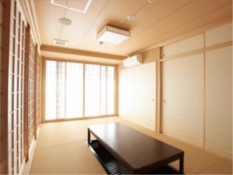 畳が敷かれた和室である。掘りごたつ式のテーブルが中央に置かれ、周囲にはふすまや格子状の引き戸がある。外光が入り込んで明るい雰囲気である。