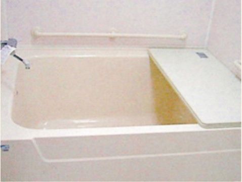 白を基調とした個室タイプの浴室である。壁に手すりが設置されており、バスタブの上には風呂蓋が置かれている。