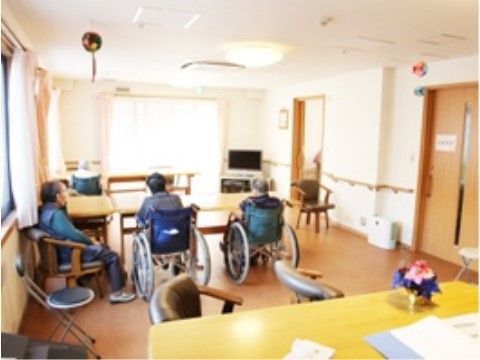 広間の角に置かれているテレビを眺めている３人の入居者様