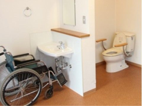 トイレ横の壁に設置された洗面台の前に置かれている車椅子