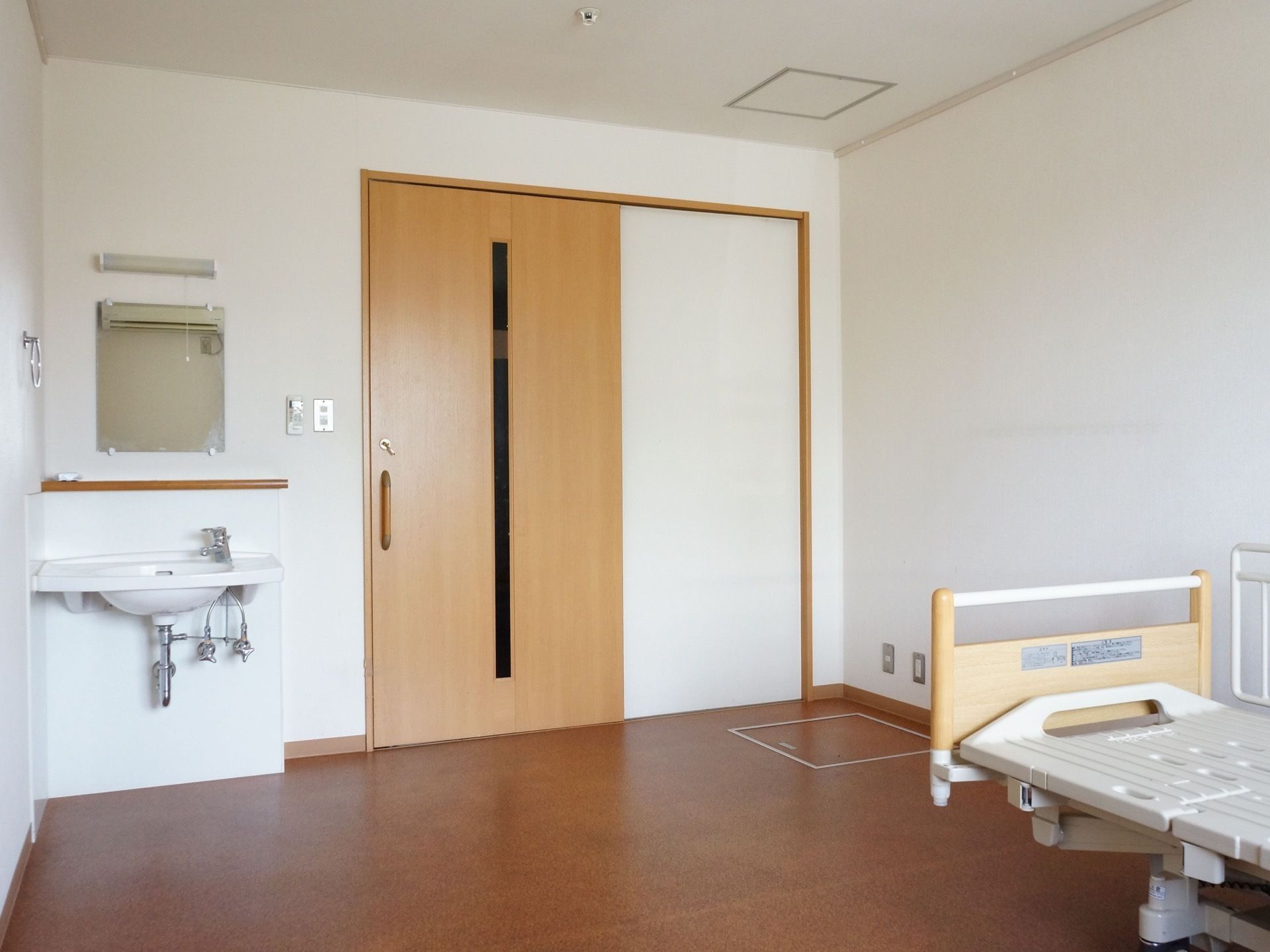 広くシンプルな居室には介護用ベッドと洗面台が備えつけられている。扉は引き戸になっており、出入りがしやすい。