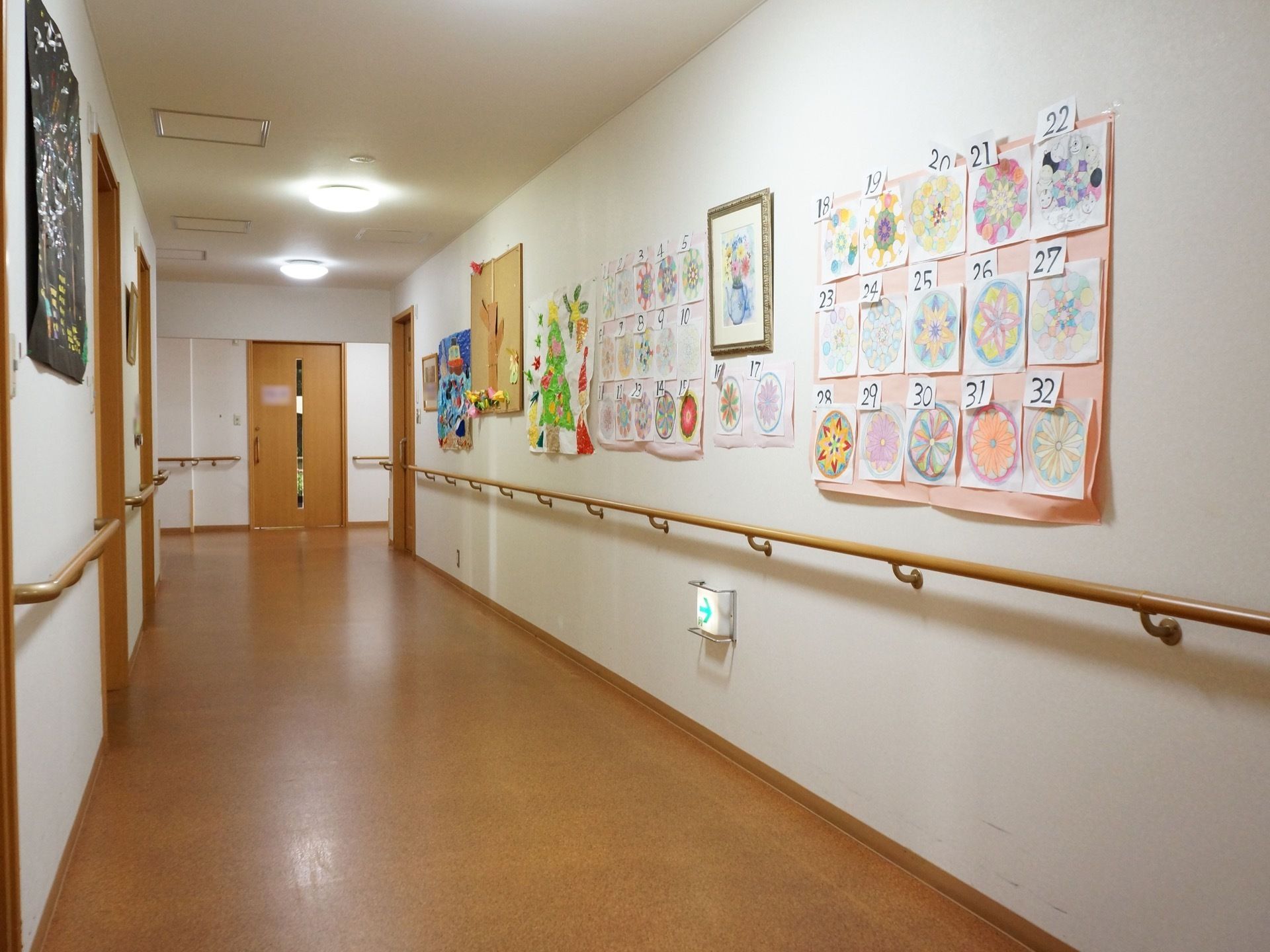 通路には手すりが途切れることなく備えつけられている。壁には入居者様の作品などが飾られており賑やかになっている。