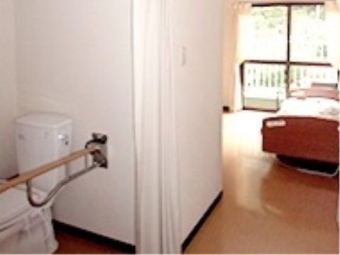 掃き出し窓があるため部屋が明るい。低床型のベッドが設置されている。トイレはしっかりした手すりが付いている。
