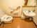 茶色の床の広いトイレがある。壁には曲線状の手すりが付いている。側には鏡と洗面台があり、物を置ける棚が付いている。