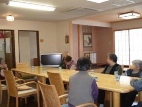 横長に並べられたテーブルセットに集まってテレビを見る入居者様