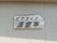 ベージュ色の壁に原木の一枚板を使った看板が設置されている。黒い文字で２段に分けて施設名が書かれている。