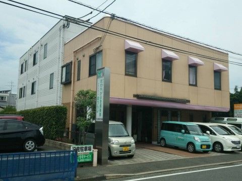 白や水色の乗用車が駐車スペースに停まっているオレンジの建物