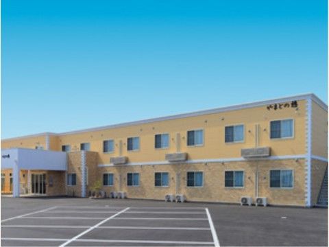 ２階建てのオレンジ色の施設の前に広がる駐車スペース
