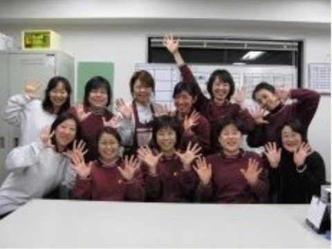 白いテーブルの向こうに２列に並んで笑っているスタッフ