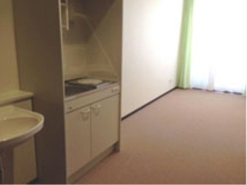 窓が大きく、明るい雰囲気の居室。簡易キッチンが設置されており、調理ができる。洗面台も完備されている。