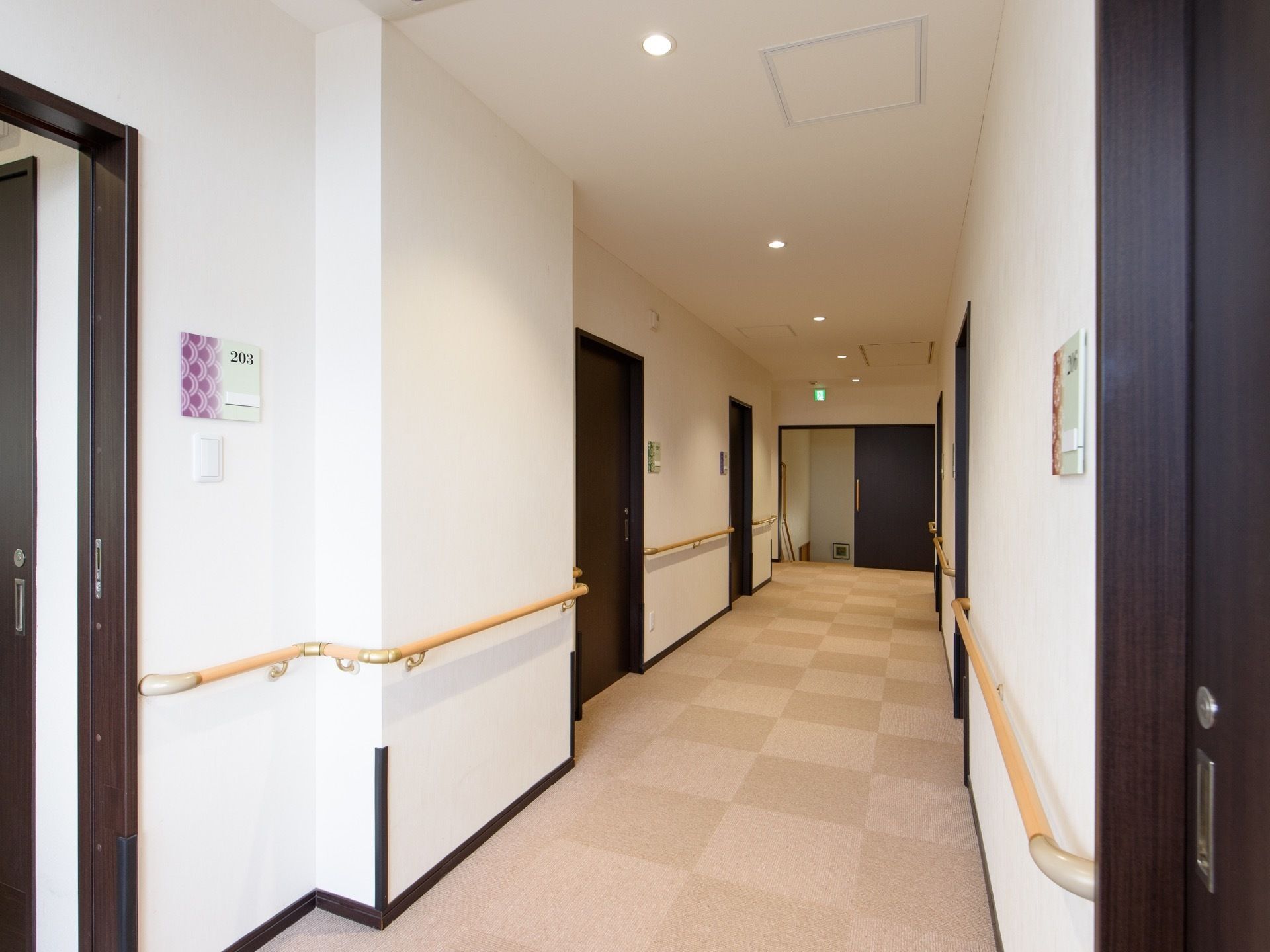 廊下の両側に居室へのドアがあり、ドアごとに壁に部屋番号の書かれたプレートが下がっている。プレートの下にスイッチがある。