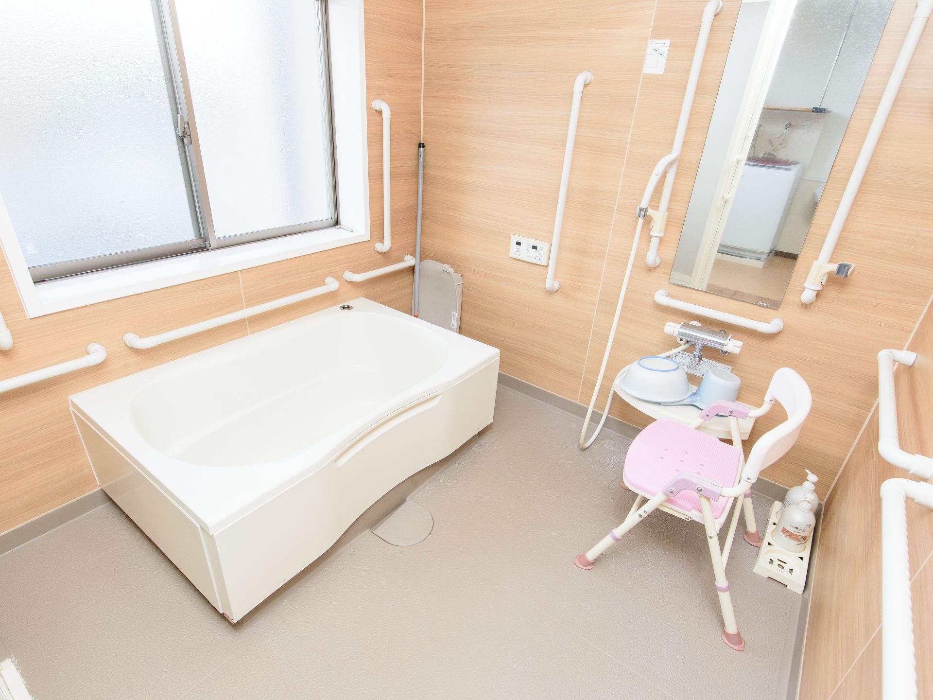 浴室の壁は木目調のシートが張られ、あたたかい雰囲気になっている。大きめのバスタブがあり、シャワー椅子が置かれている。