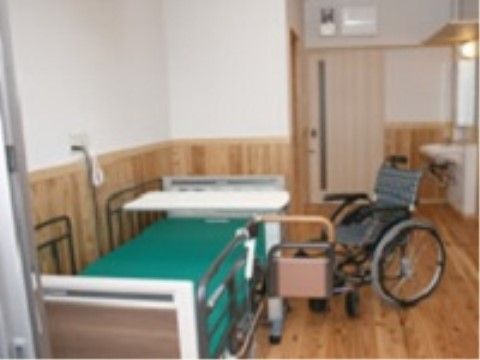 ベッドと車椅子が置かれている居室には、洗面台が備え付けられている。フローロングや木の腰壁から木の温かみを感じられる。