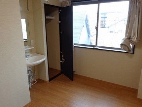 窓の前にクローゼットと洗面台が並んでいるフローリングの部屋