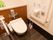 木目調の床を採用したトイレである。横側の壁際にL字型の手すり、ナースコールなどを設置している。後方は小物が置ける棚になっている。