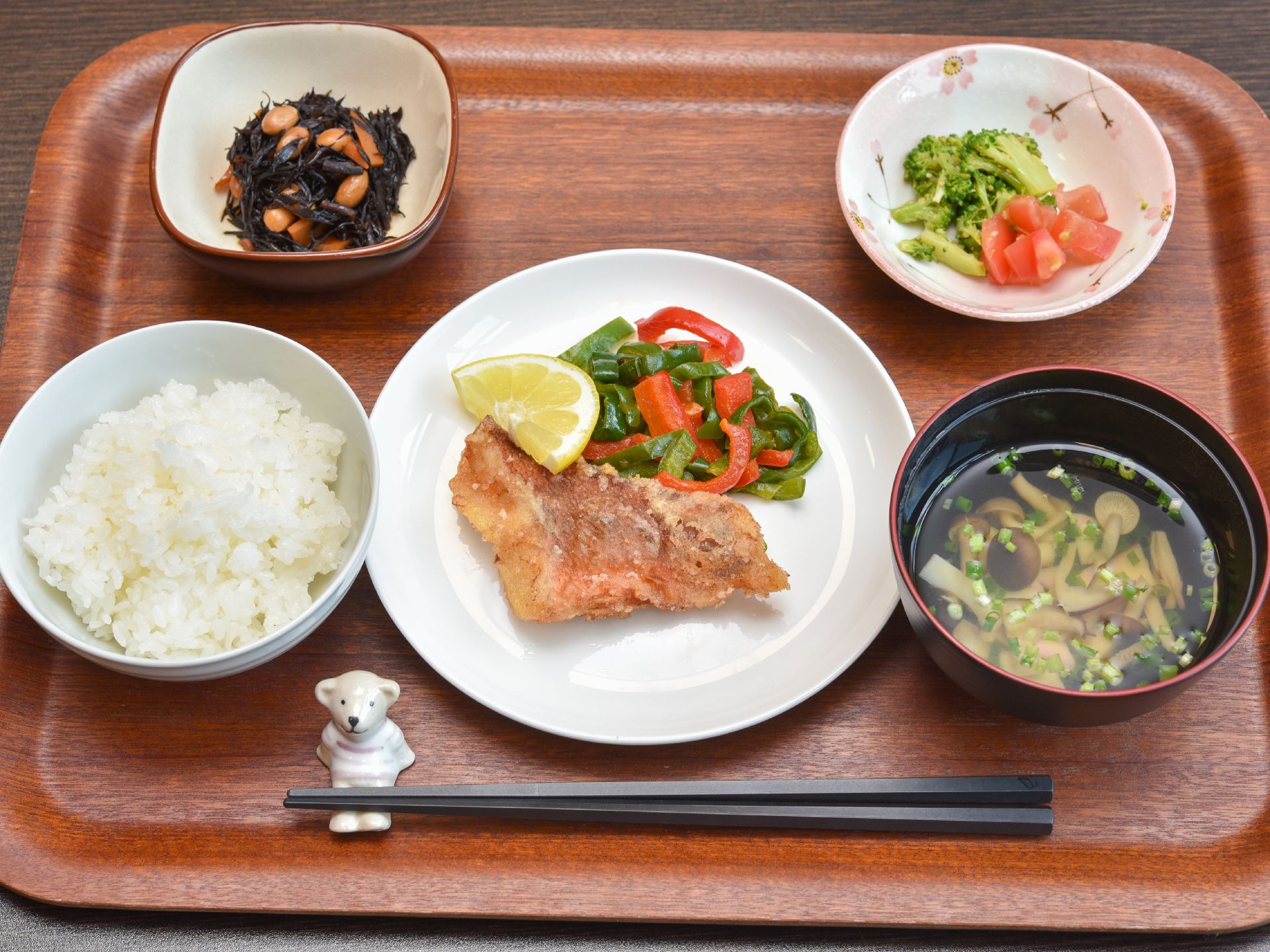 今日のメニューは魚の揚げ物に炒め野菜、ひじきの煮物、サラダ、お吸い物、ご飯。栄養バランスや彩りやおいしさに配慮されている。