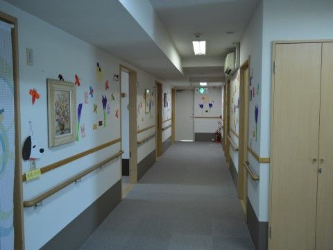廊下の壁には手すりが備え付けられており、折り紙などで作られた花やトンボが飾られているため、華やかになっている。
