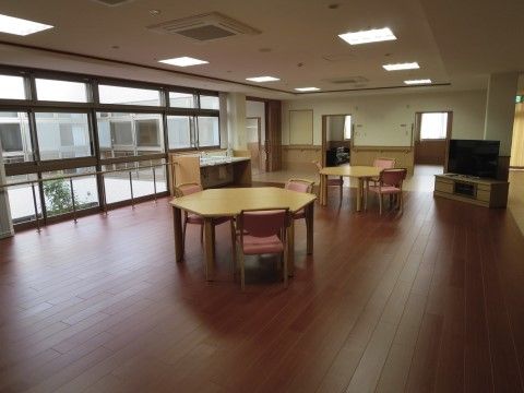 六角形のテーブルが並んだ機能訓練室。大型のテレビが備え付けられている。食事やレクリエーション、団欒の場として使用できる。