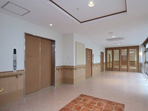 木目調の扉のエレベーターは大きく、車椅子での出入りもストレスなく行うことができる。壁には手すりが備え付けられている。