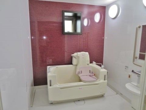 足腰が弱く一人で浴槽に入れない入居者様のために、座位入浴ができる介護浴槽を完備している。ワインレッドの壁がおしゃれな浴室。