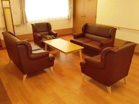 １人掛けソファが２脚、２人掛けソファが２脚置かれたソファセットがある。周囲の壁には移動補助用の手すりが設置されている。