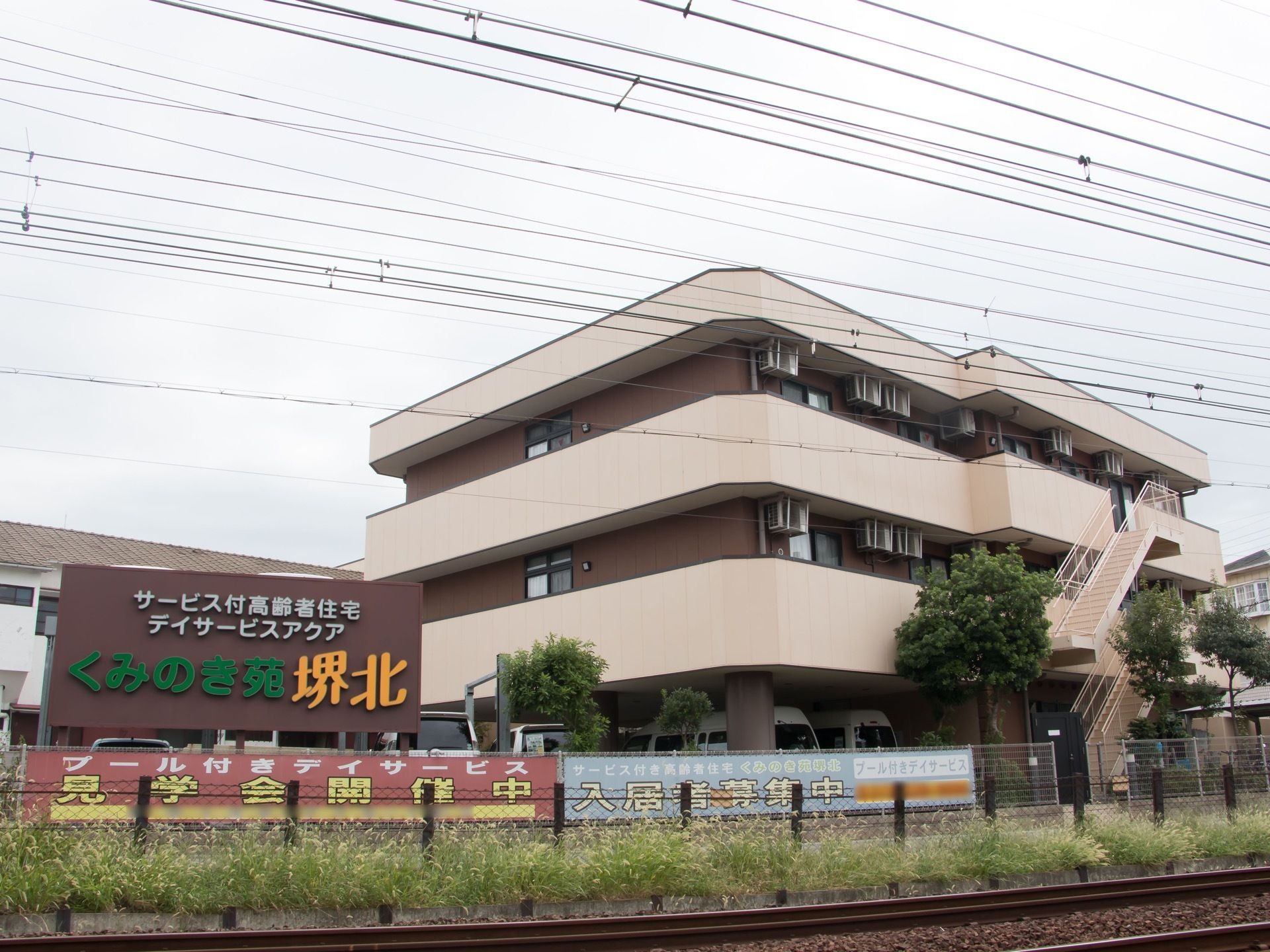 施設建物は線路沿いに建てられている。電車側から、あるいは線路越しに見えるように大きな看板が立てられている。