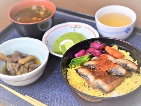 黒い四角いトレーに配置された天ぷらと野菜の小鉢の付いた和食セット