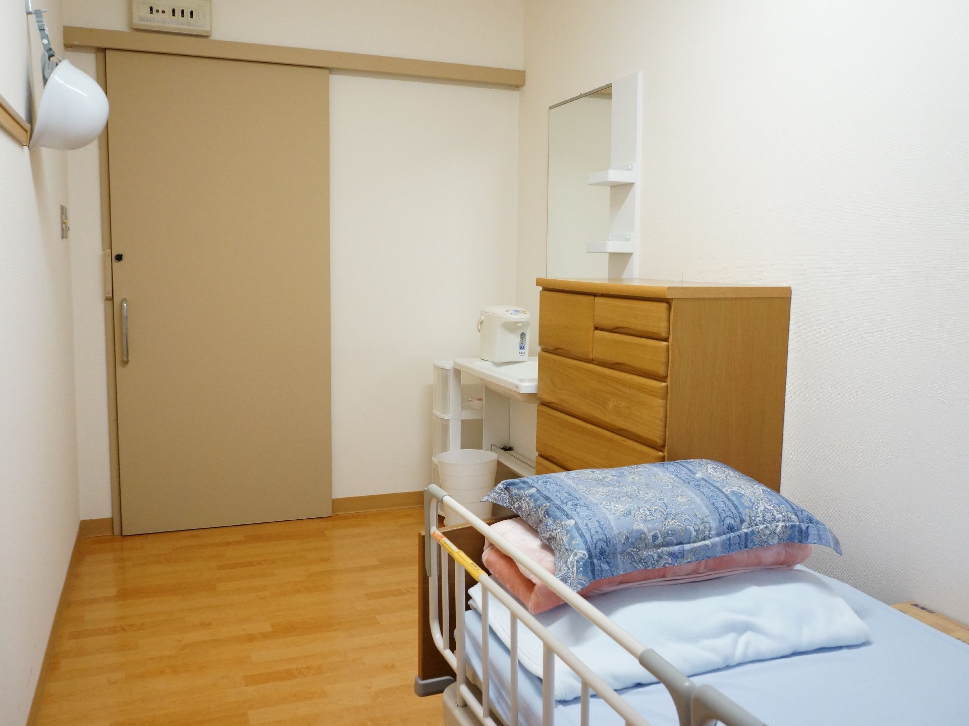 居室の内側で、収納タンスや洗面台が設置されている。入口は、出入りのしやすい引戸が取りつけられている。