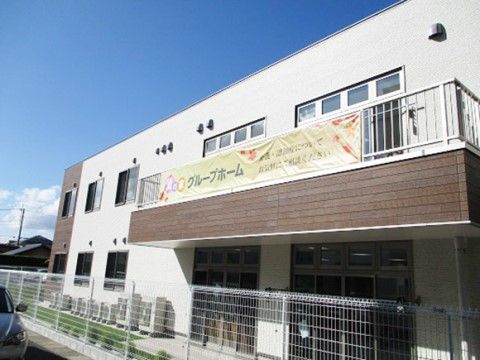建物周囲を白いフェンスで囲まれている、白と茶色の建物