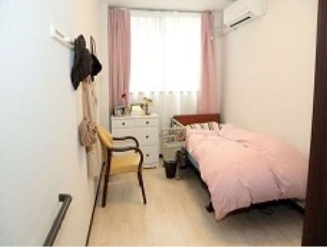 ピンクの厚手の掛布団が敷かれたベッドがある１人用の部屋