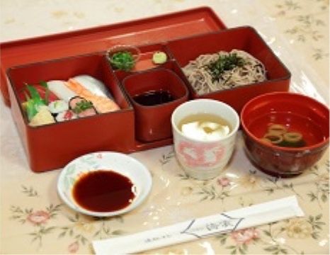 蕎麦の皿と寿司の皿が並んだ幕ノ内弁当のような器が配膳されているテーブル