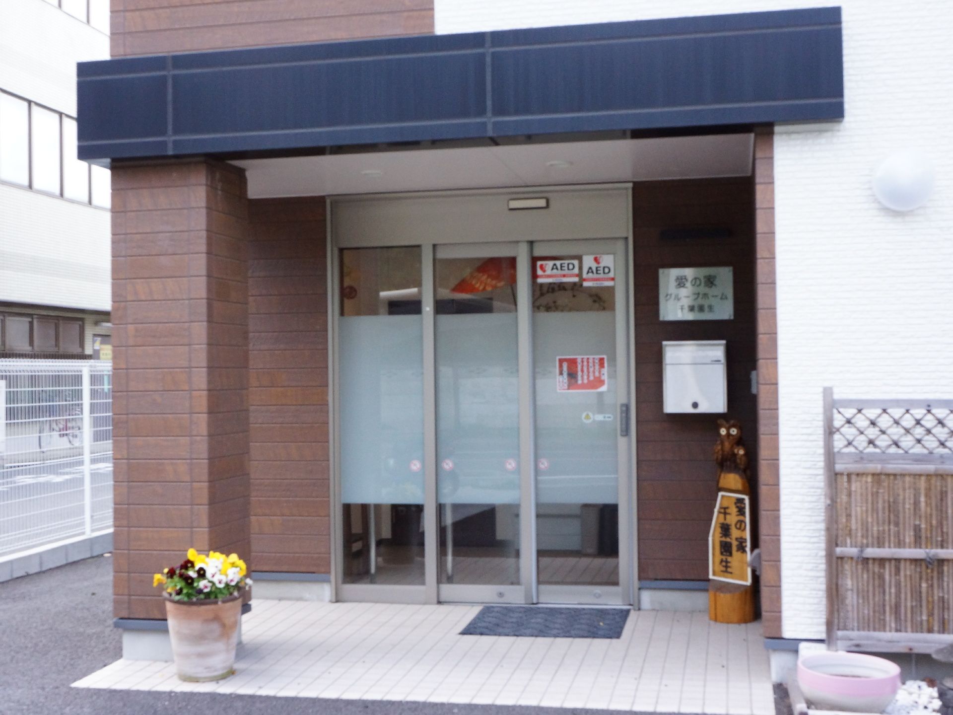 一見グループホームには見えないような落ち着いた色合いの建物。入口横には花があり明るく優しい雰囲気がある。