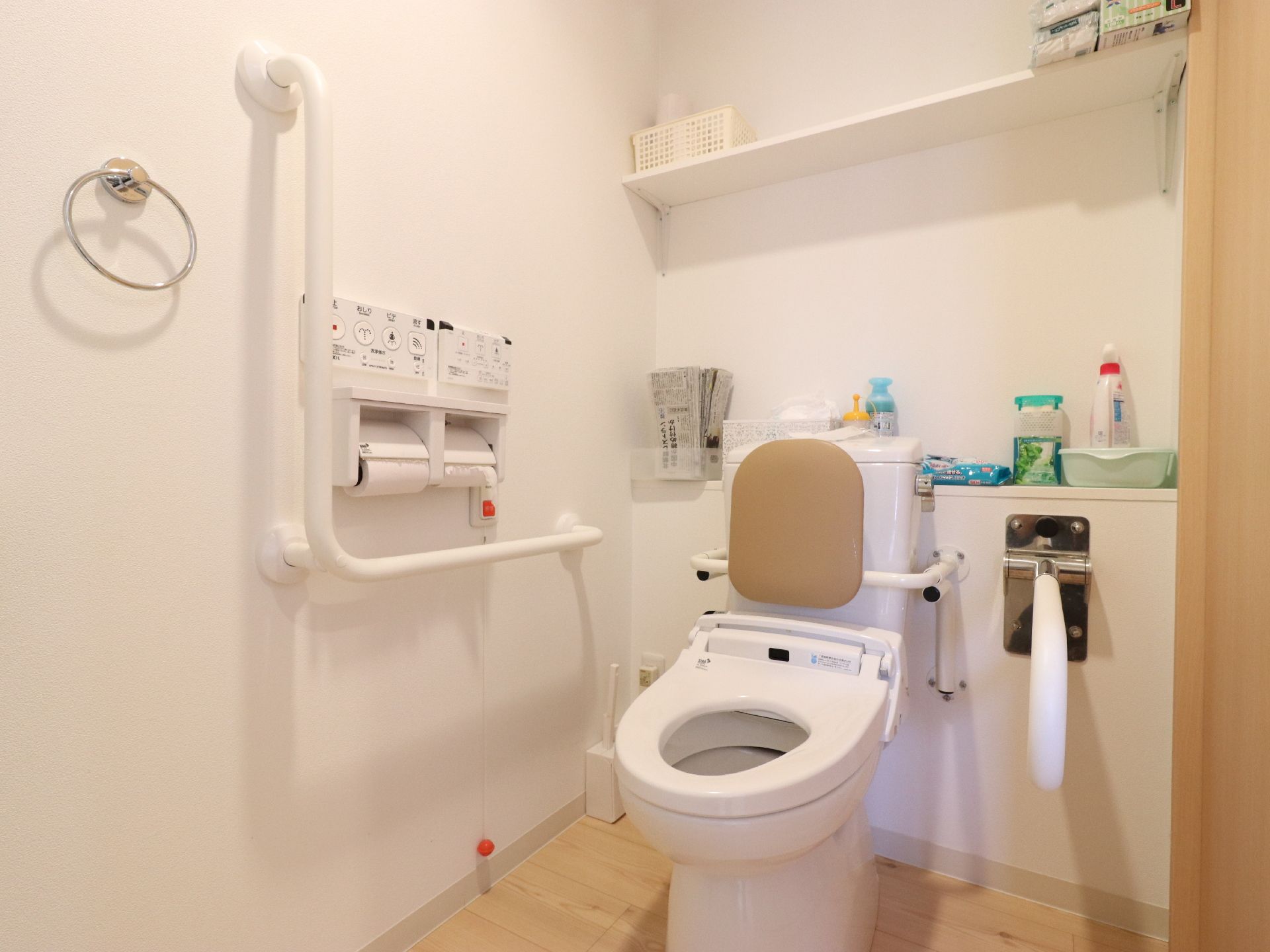 トイレには、背もたれや手すりが設置されており、安全に利用することができる。温水洗浄便座になっていて、ボタンが壁についているので使いやすい。