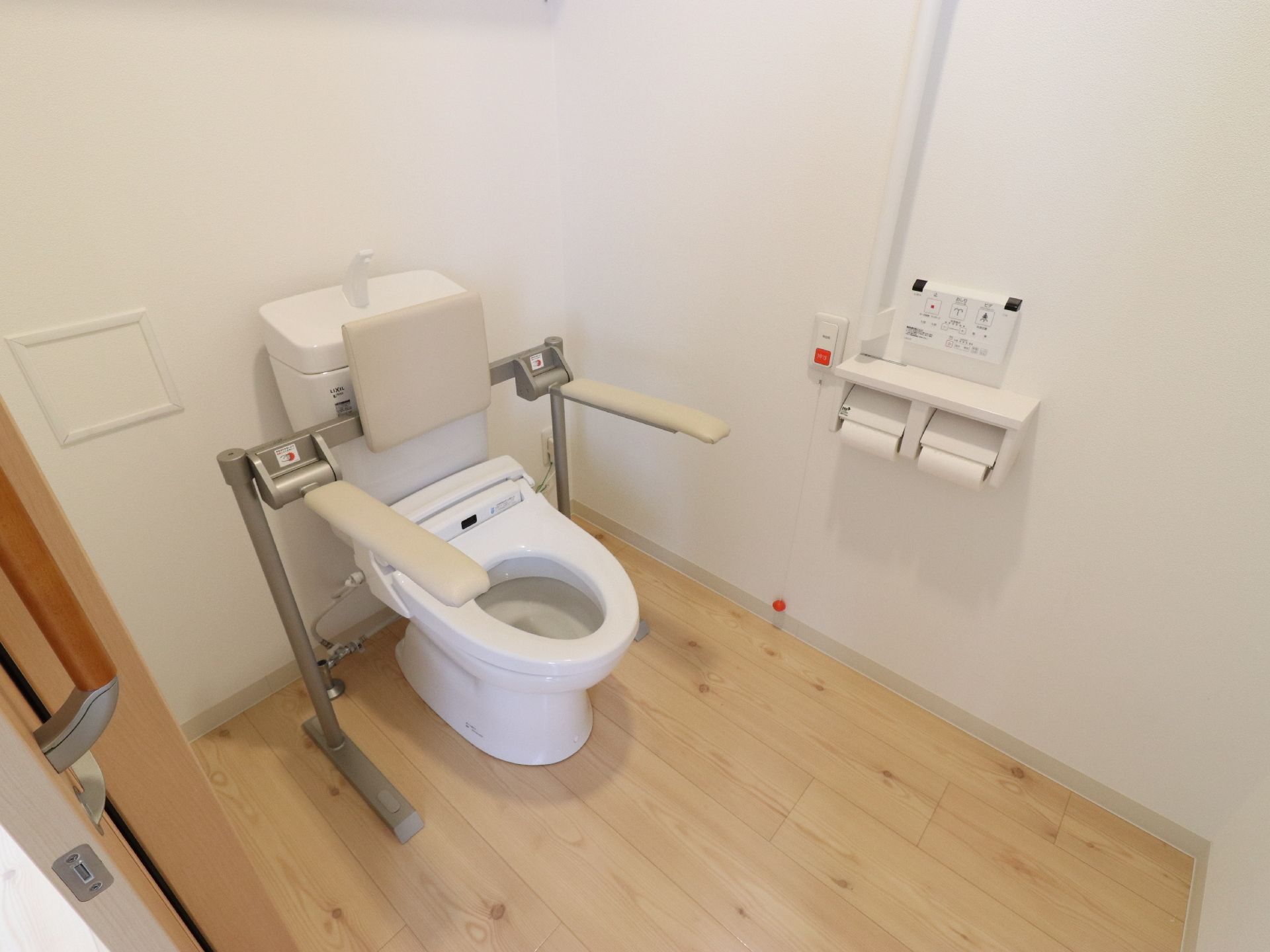 広々としたトイレは明るく清潔感がある。可動式の背もたれとひじ掛けがついていて安全に利用することができる。