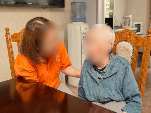 アンティーク調の椅子に座った女性入居者様に声を掛けるスタッフ