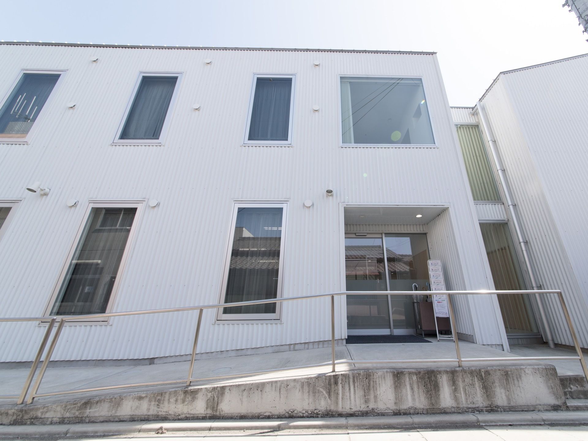 施設の建物はガラス張りの部分が多く、内部の見通しが良い。前面にはスロープを設置し、道路側には手すりを取り付けている。
