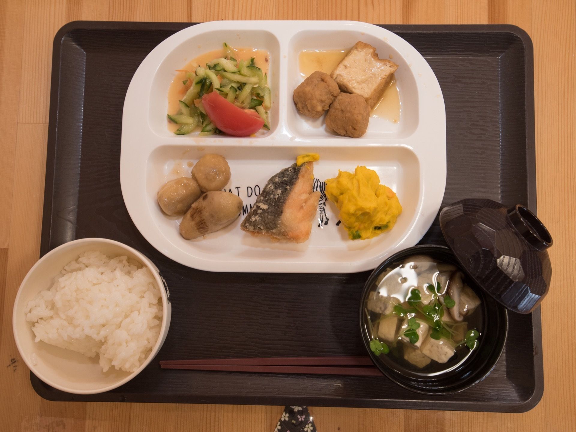 魚が主菜で野菜もたくさん入った献立になっている。ご飯やお吸い物もあり、ボリュームも十分である。黒いトレーに載せて提供をしている。
