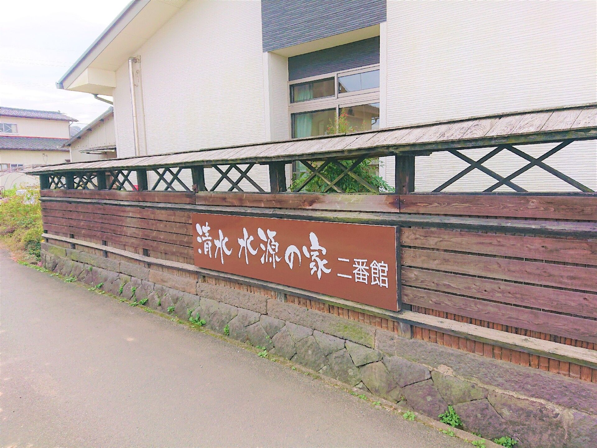 施設の周りを囲む木材のフェンスに設置された施設名の書かれた看板