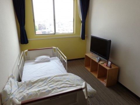 電動式のベッドが配置され、寝起きがしやすくなっている。淡いイエローの壁が明るさと穏やかさを感じさせる。