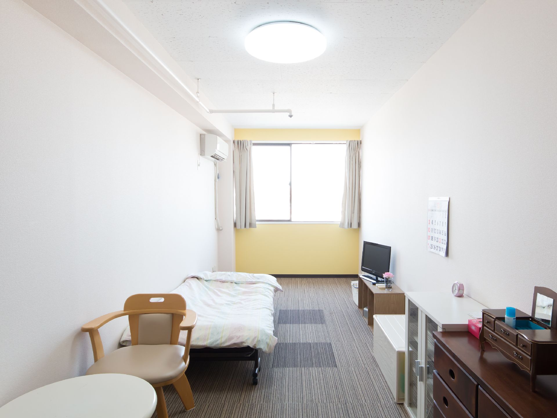 黄色と白で壁が塗り分けられている、照明がとても明るい居室