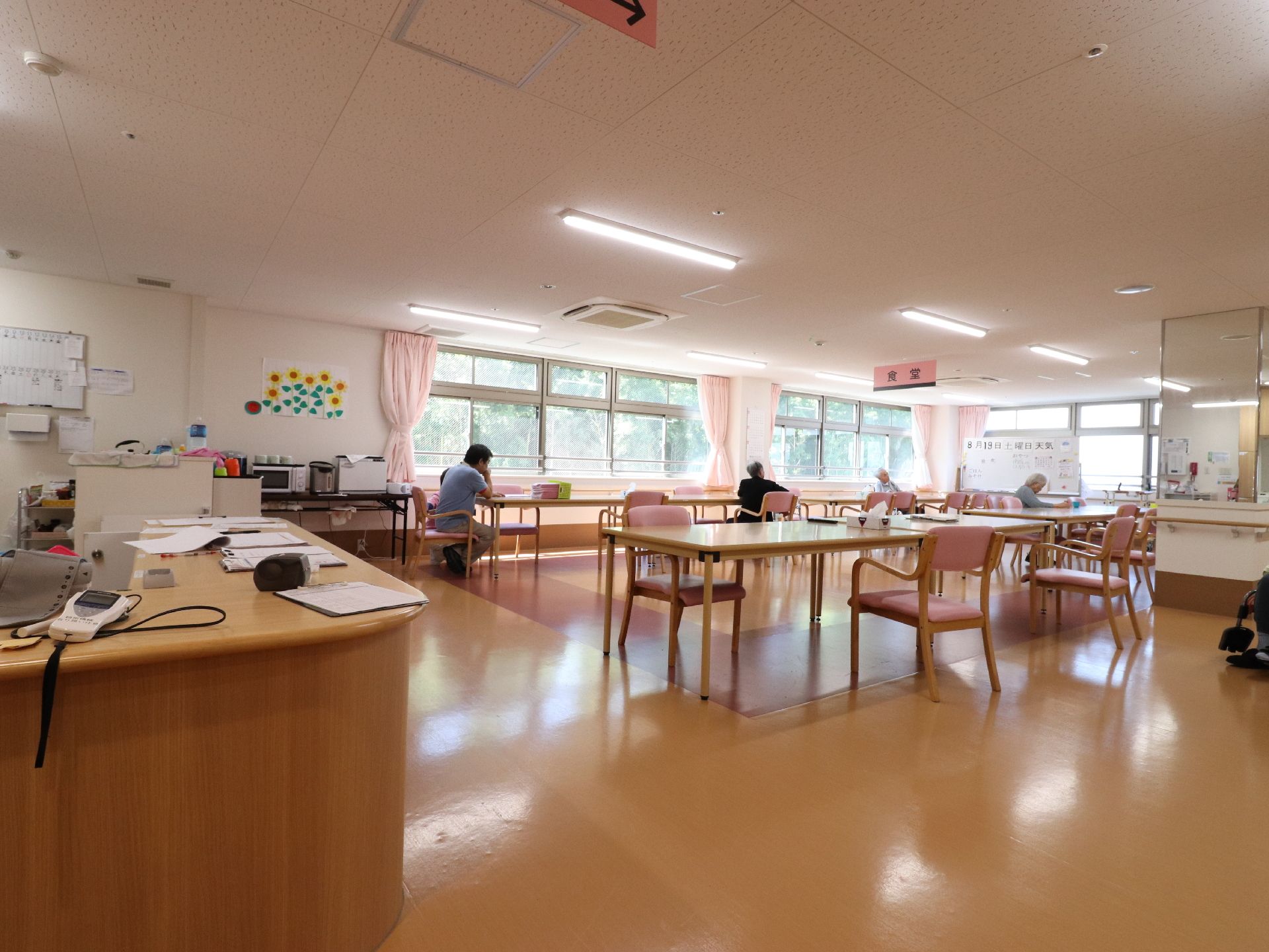 施設の各階には食堂がある。各テーブルに椅子が数台置いてあり、車いすで座れるスペースが確保されている。数人の入居者がゆっくり過ごされている。