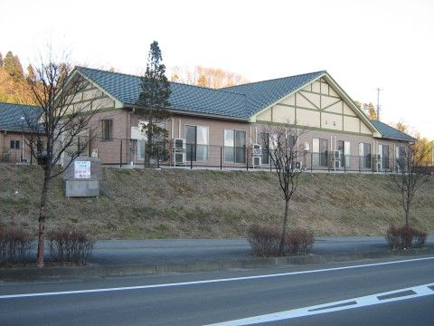 芝生が植えられた土の高台の上に建っている、青い屋根の建物