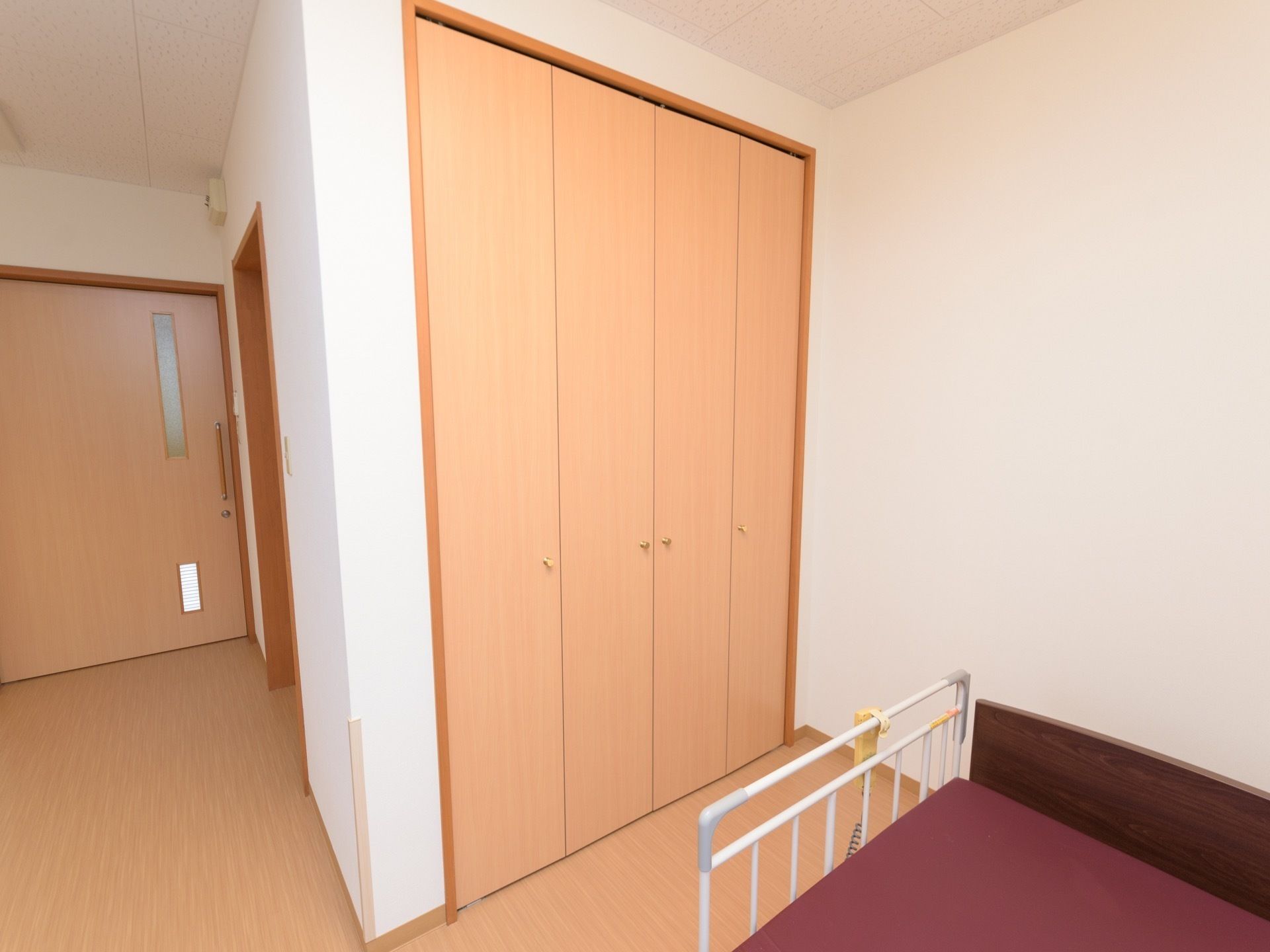 居室内に完備されている収納クローゼットである。明るい木目調で折りたたみ式の両開き扉が設置されている。
