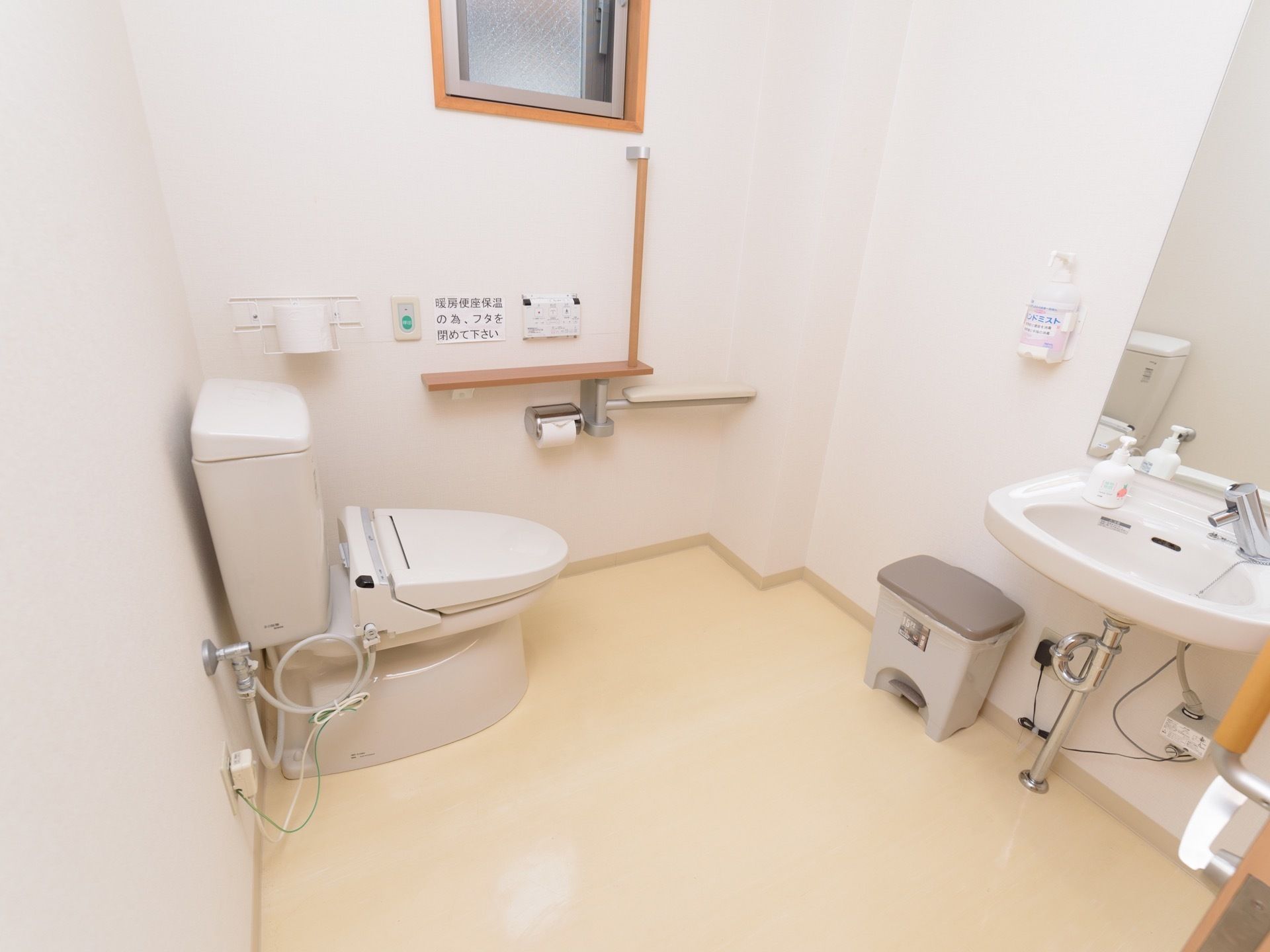 窓が設置され、広くスペースが確保されているトイレには、体勢保持のための手すりや器具が壁に取り付けられている。