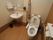 共有のトイレである。個室の中に洋式便器と手洗い台があり、ゆとりのあるスペースが取られている。便器の両脇には手すりがある。