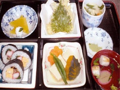 五目太巻きや飾り切りがされた野菜の煮物、天ぷらなどが並ぶ献立