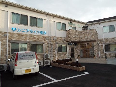 施設で所有している白い軽自動車が１台停まっている施設前